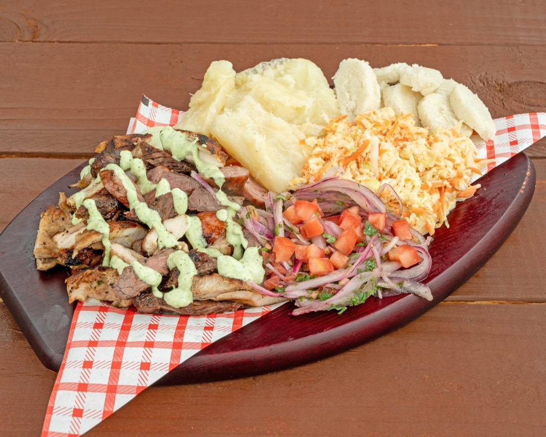 Parrilla mixta platter with grilled picaña, chicken, chuleta and chorizo with yuca and sides
